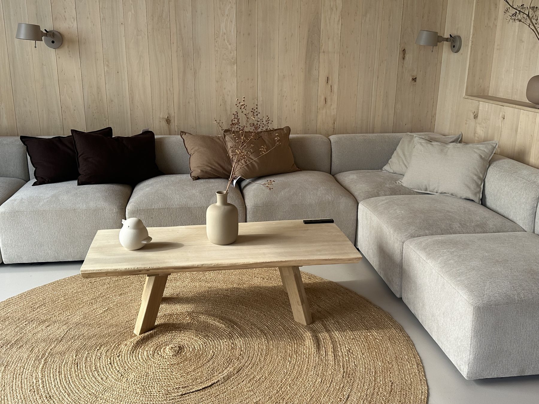 Ruime lichte hoekbank tegen een houten wand