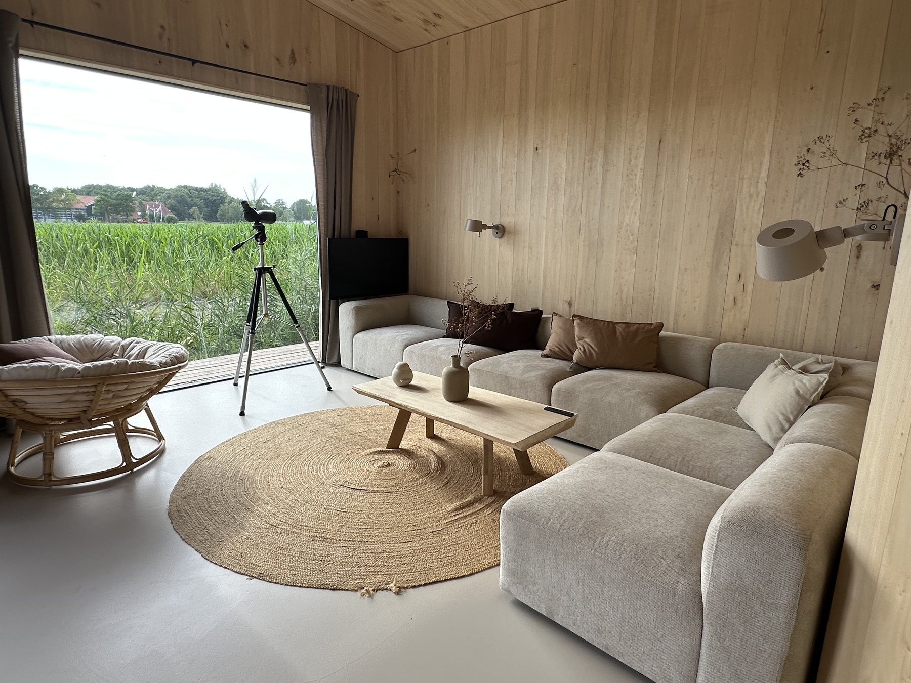 Woonkamer met panoramaraam en uitzicht over het riet